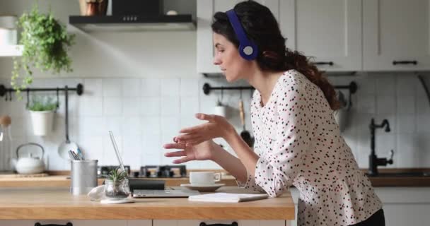 Жінка в навушниках працює віддалено з колегою по відеозв'язку — стокове відео