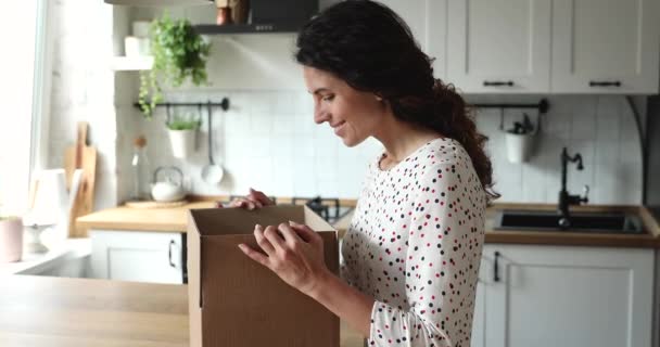 Kobieta otwiera paczkę wygląda wewnątrz czuje się zadowolony z zamówionych przedmiotów — Wideo stockowe