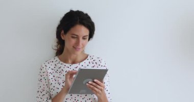 Stüdyonun arka planında duran kadının elinde tablet cihazı var.