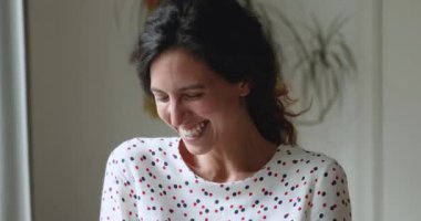 Evin içinde duran güzel bir kadın şakaya gülüyor ve kameraya bakıyor.