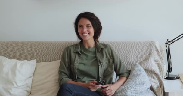 Mulher sentada no sofá segurando controle remoto assistindo filme de comédia — Vídeo de Stock