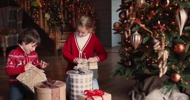 Gelukkige kinderen openen geschenkdozen op kerstochtend — Stockvideo