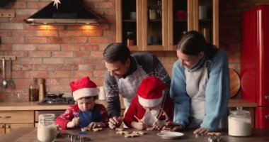Çocuklu bir aile önlük giyer, mutfakta Noel kurabiyesi hazırlar.