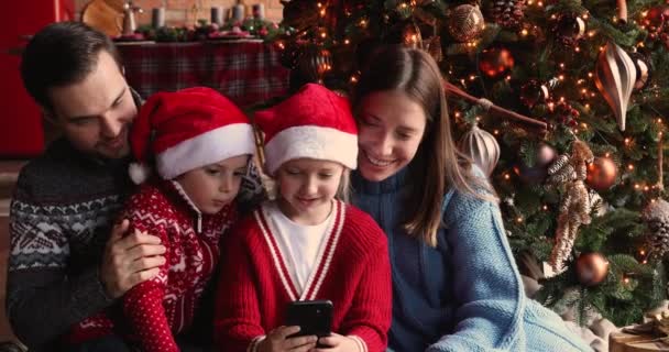 Famiglia con bambini riuniti vicino all'albero di Natale con smartphone — Video Stock