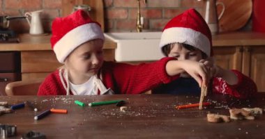 Küçük kardeşler masada oturup ev yapımı xmas kurabiyeleriyle oynarlar.