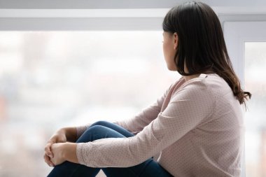 Üzgün genç bir kadın uzaklarda bir yere bakıyor.