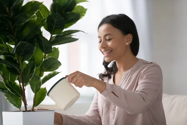 Sorrindo biracial mulher água verde casa planta — Fotografia de Stock