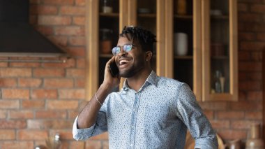 Gülümseyen melez genç adam cep telefonuyla gülüyor.