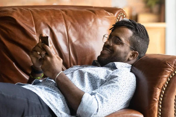 Happy young biracial man relax on sofa using smartphone — Stok Foto