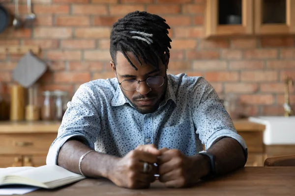 Sad biracial man feel distressed thinking at home kitchen