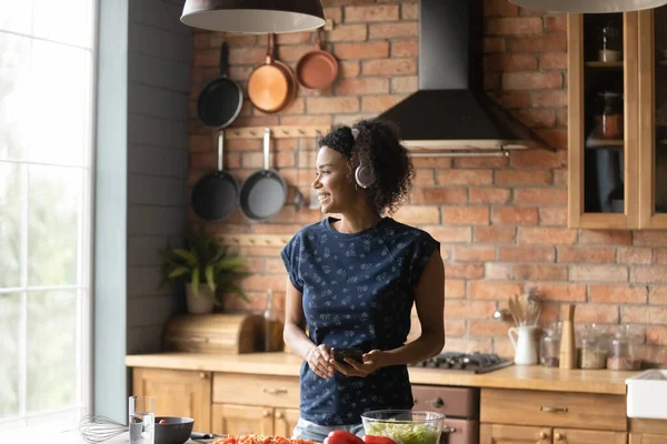 Sonriente mujer afroamericana escuchar música cocinar —  Fotos de Stock