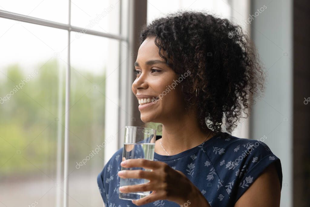 Smiling African American woman drink water from glass