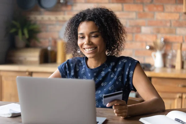 Smiling biracial female make payment on laptop online