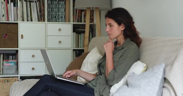 Pensiv affärskvinna som arbetar hemifrån på laptop sittande på soffan — Stockvideo