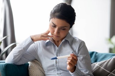 Hintli kadın hamilelik testine bakıyor. Sonuçları bekliyor.