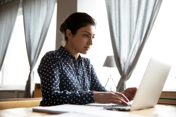 Индийская деловая женщина сидит за столом и работает над ноутбуком — стоковое фото