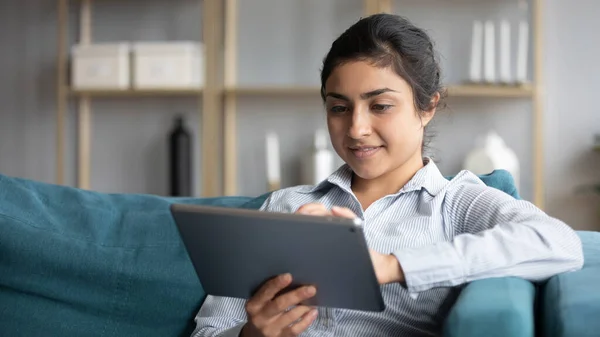 印度女人靠在沙发上，手握平板电脑，享受网上购物 — 图库照片