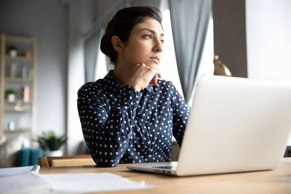 Thoughtful Indian female distracted from computer work looking into distance — Stock Photo, Image