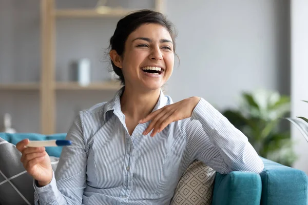 Indian female sit indoor hold pregnancy test laughing feels happy — Stock Photo, Image