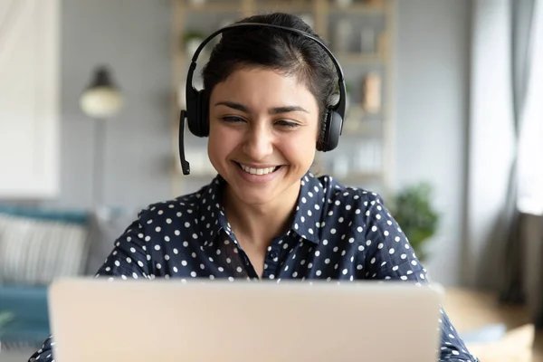 Indian woman wear headset looks at laptop talk by videocall — Stock Photo, Image