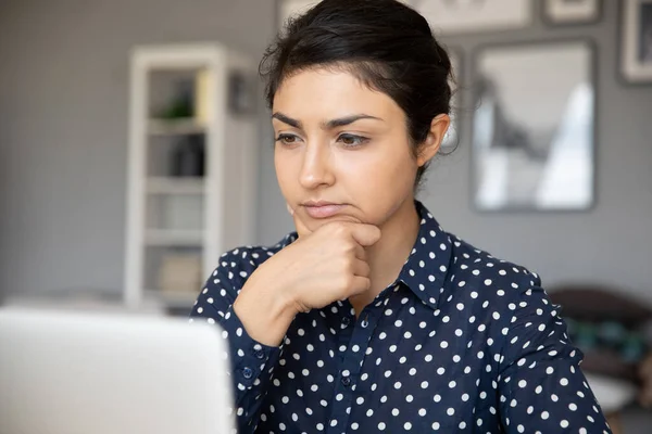 Indian businesswoman looks at laptop screen thinks over task — Stock Photo, Image