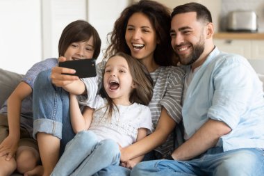 Mutlu ebeveynler ve iki sevimli çocuk selfie için poz veriyorlar.