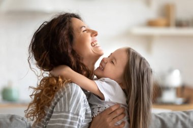 Neşeli genç anne ve kızının kucaklaşması ve gülmesi.