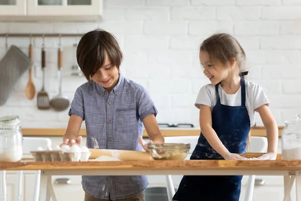 Twee gelukkige kleine kinderen die samen koken, deeg uitrollen — Stockfoto