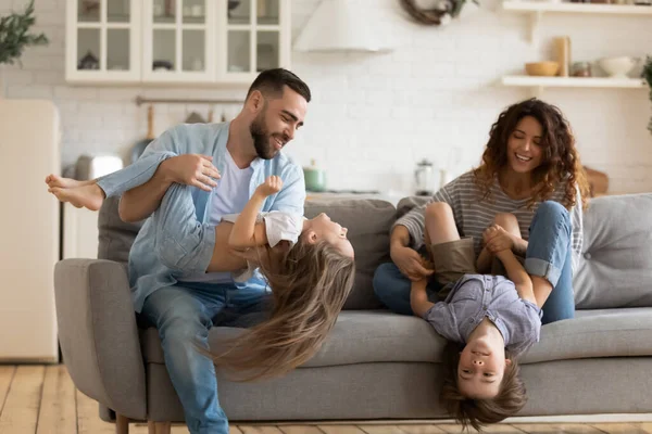Glückliche junge Eltern spielen zu Hause mit zwei kleinen Kindern — Stockfoto