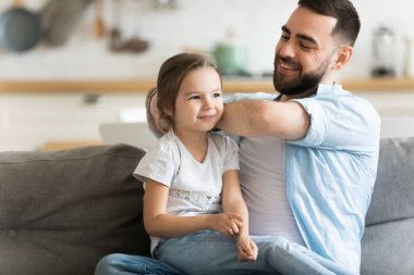 Umursayan, gülümseyen baba tarayan sevimli anaokulu kızının saçlarını
