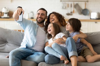 Çocuklu mutlu ebeveynler eğleniyor, mobil cihaz kullanıyorlar.