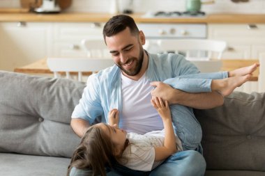 Mutlu genç baba evde sevimli küçük kızıyla oynuyor.