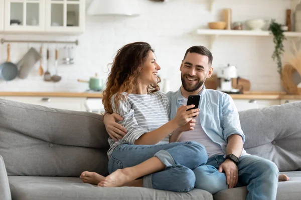 Glückliches junges Paar nutzt gemeinsam Smartphone, entspannt auf der Couch — Stockfoto