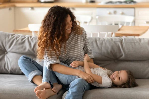 Glimlachende jonge moeder spelen grappig spel met schattige kleine dochter — Stockfoto