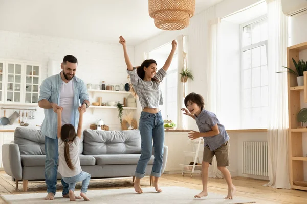 Счастливые родители с детьми танцуют в современной гостиной — стоковое фото