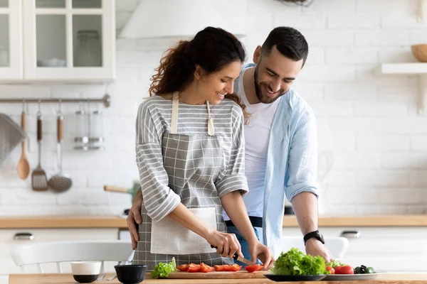 Glückliches Liebespaar bereitet gemeinsam Abendessen in der Küche zu, umarmt sich — Stockfoto