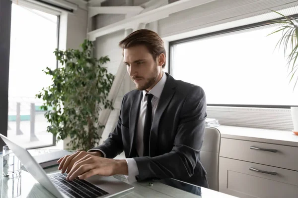 Motivated young corporate male employee working on computer.