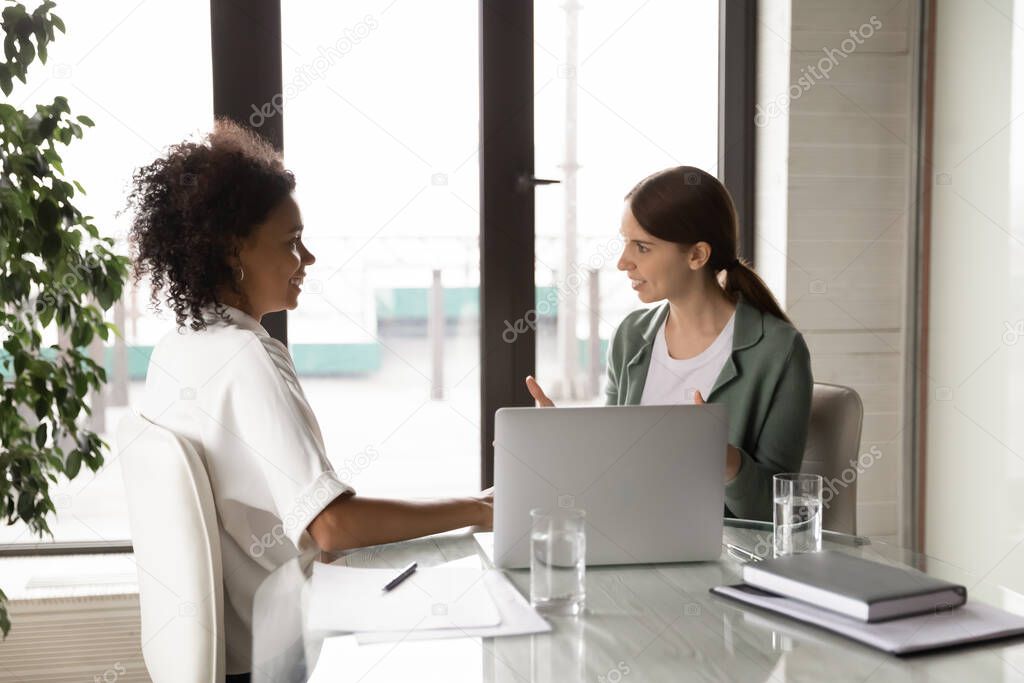 Smiling young mixed race diverse businesswomen talking at office.