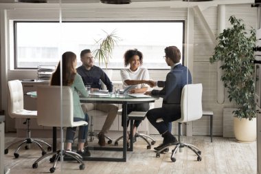 Erkek lider toplantıda mutlu bir Afrikalı işçiyle el sıkışıyor..