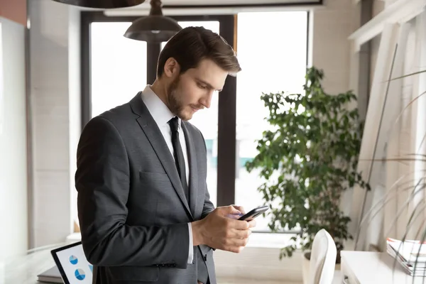 Fokuserad ung affärsman som använder smartphone på kontoret. — Stockfoto