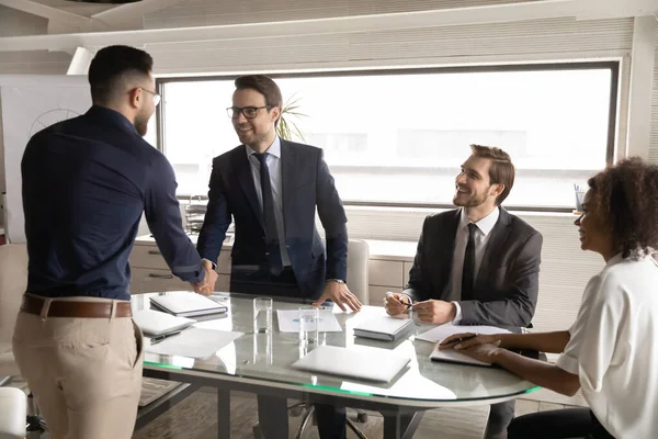 Glückliche kaukasische Geschäftsleute in den 30er Jahren geben ihrem arabischen Partner die Hand. — Stockfoto