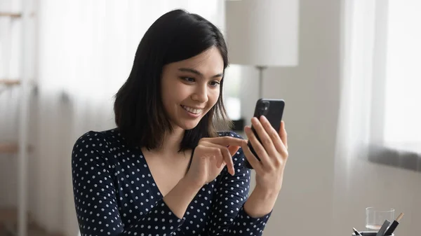 Feliz chica asiática mira la pantalla del teléfono inteligente hablando en la web — Foto de Stock