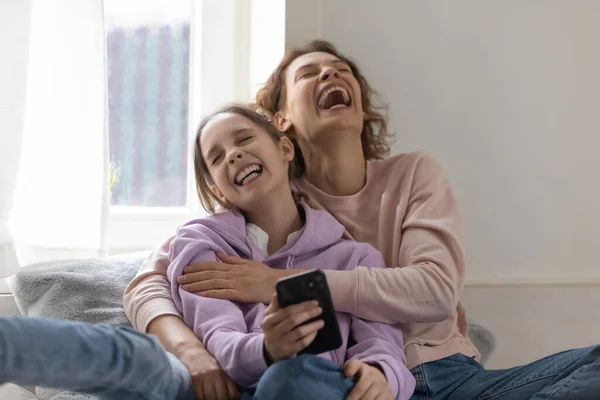 Madre y hija adolescente se ríen con un teléfono inteligente —  Fotos de Stock