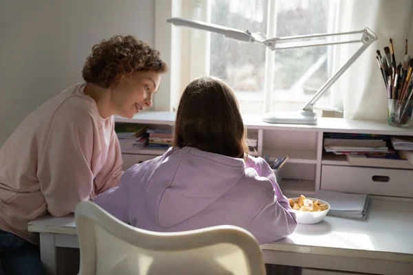 Vista trasera de la mamá ayudando a la hija adolescente con la tarea — Foto de Stock