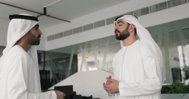 Kendine güvenen iki ciddi Arap iş adamı ofiste konuşuyor, el sıkışıyor, anlaşmalar yapıyor, pazarlık üstüne anlaşma, görüşme, danışma, ortaklık kurma.