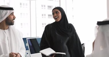Geleneksel elbiseli genç Arap profesyonellerden oluşan iş ekibi ofiste konuşuyor, takım çalışmasını tartışıyor, proje üzerinde beyin fırtınası yapıyor, fikirleri paylaşıyor, yatırım planları yapıyor.