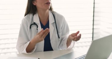 Dost canlısı, kendine güvenen, gözlüklü kadın GPS doktoru klinik ofis çalışma masasında hastayla konuşuyor, teşhisi açıklıyor, terapi için danışmanlık yapıyor. Profesyonel bir kadının kırpılmış görüntüsü.