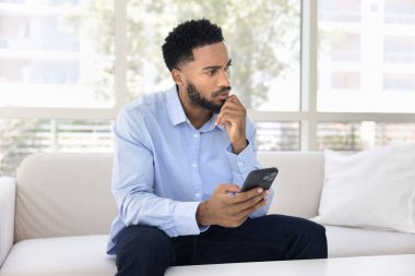 Düşünceli ciddi nesil z erkek kanepede cep telefonu kullanın Düşüncelere dalmayın kripto ticaret anlaşma sonuçları tahmini arama yapmadan önce metin yazma planı iş görüşmesi üzerinde düşünün