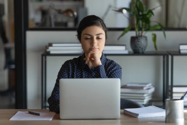 Ciddi Hintli kız öğrenci çalışmak için dizüstü bilgisayar kullanıyor, çevrimiçi öğreniyor, webinar izliyor, sanal iş eğitimi alıyor, konferans veriyor. Bilgisayarda çalışan genç bir ofis çalışanı, e-posta mesajı okuyor.