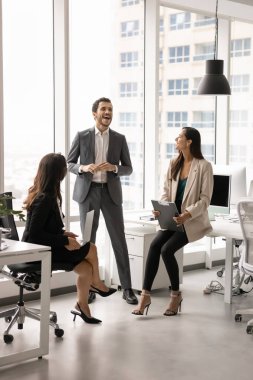 Üç farklı iş arkadaşından oluşan küçük bir ekip işyerlerinde ofis alanında duruyor, konuşuyor ve gülüyor, iş molalarının keyfini çıkarıyor, birlikte vakit geçiriyor, takım çalışması planlıyor, fikirler üzerinde kafa patlatıyor.